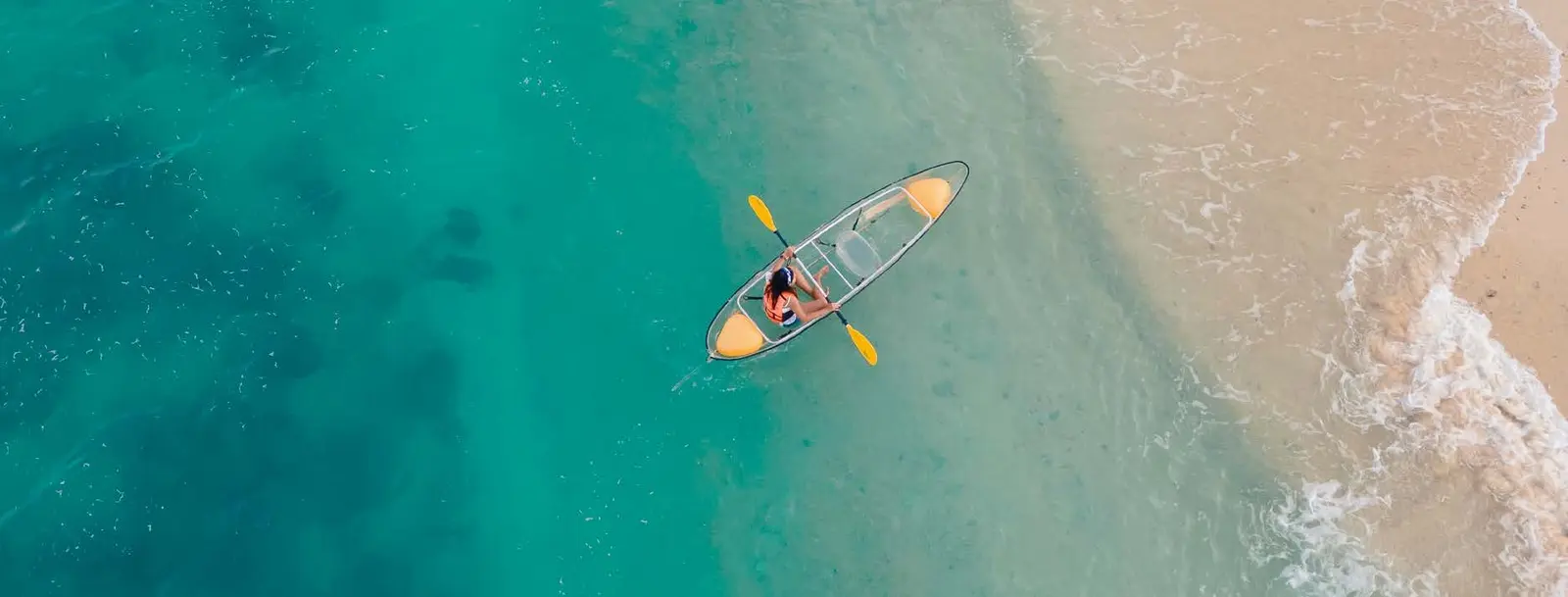 Clear glass kayaking over crystal clear turquoise waters along coastal paradise bordering Capeside Marina Residences on Sobha Siniya Island.