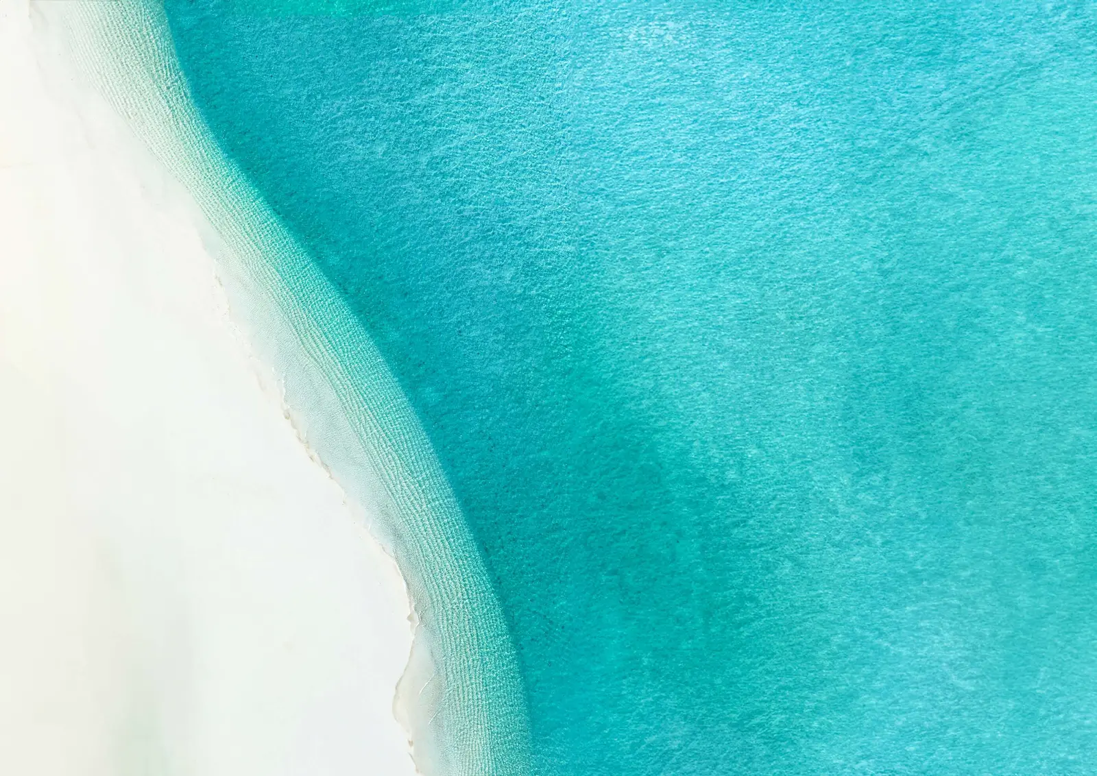Pristine turquoise sea waters and white sand coastline surrounding Pearlside Marina Residences at Sobha Siniya Island Umm Al Quwain.