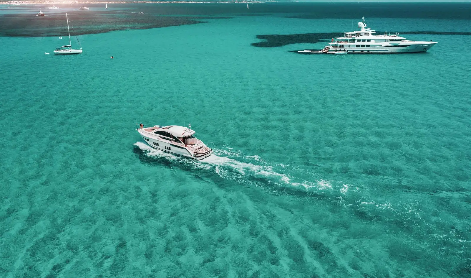 Yachtside Marina Residences at Sobha Siniya Island luxury private yachts cruising across pristine turquoise coastal waters
