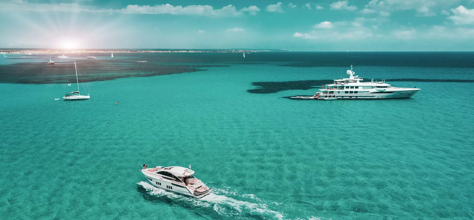 Yachtside Marina Residences at Sobha Siniya Island Umm Al Quwain luxury private yachts sailing in azure waters