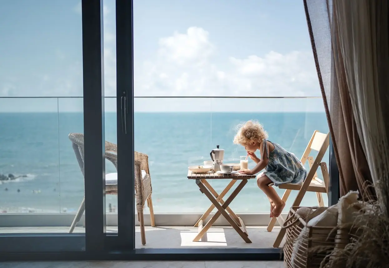 Child enjoying breakfast on sunny private balcony overlooking the Arabian Sea at Bayfront Marina Residences apartments